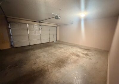 Spacious garage interior with concrete flooring and overhead lighting, part of a two-story home in West Little Rock.