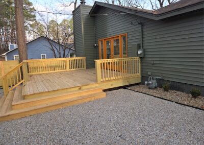 Upgraded home exterior with wooden deck, gravel pathway, and modern green siding in West Little Rock.