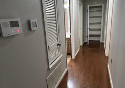 Hallway in West Little Rock single-family home featuring hardwood flooring, thermostat, and open closet space, showcasing the interior layout and upgrades.