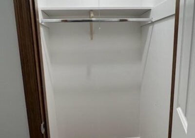 Empty closet with a hanging rod and shelf, showcasing storage potential in the West Little Rock single-family home for rent.