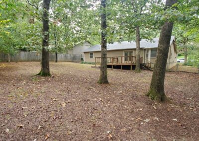 Single-family home in West Little Rock featuring a spacious backyard with trees and a deck, highlighting outdoor living space for potential renters.