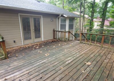 Spacious wooden deck of a single-family home in West Little Rock, featuring double doors leading to the interior, surrounded by greenery and a private backyard.