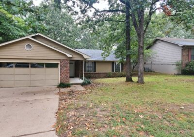 Single-family home in West Little Rock, featuring a landscaped front yard, garage, and surrounding trees, showcasing a spacious and inviting exterior.
