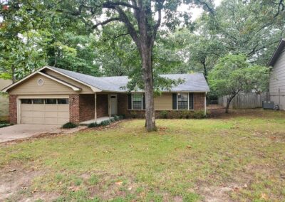 Single-family home in West Little Rock featuring a brick facade, large front yard, and garage, ideal for rental options.